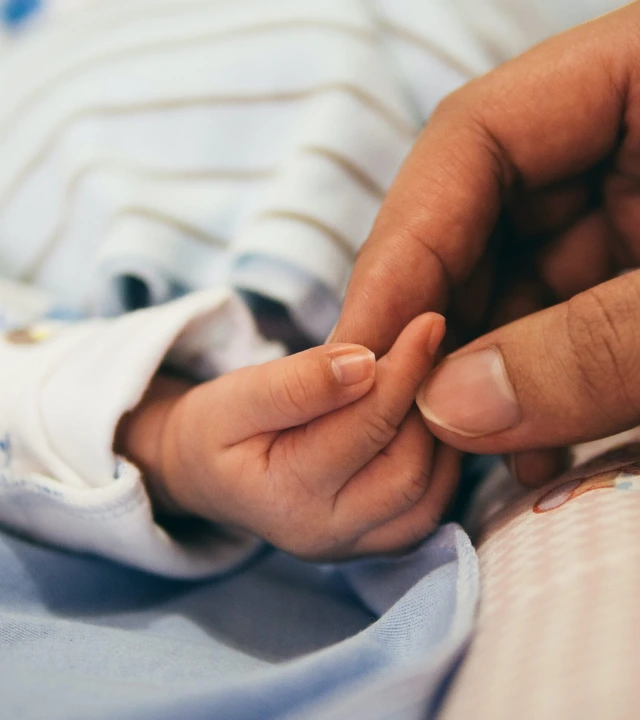 Parent holding baby's hand